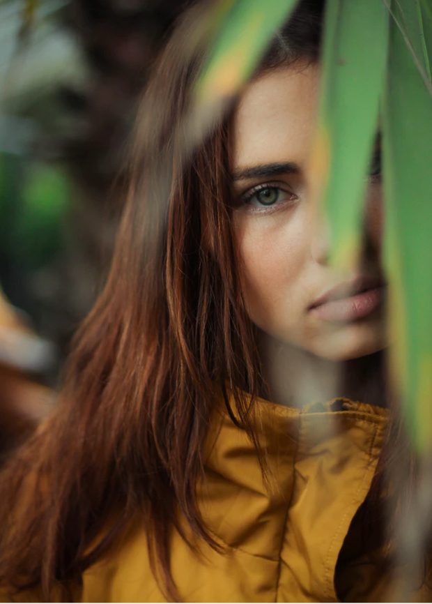 photo of Willow looking at camera, palm leaf covering half her face