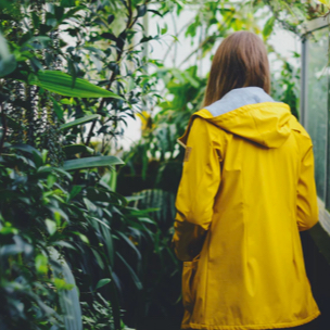 Willow entering a leafy garden wearing a mustard yellow jacket